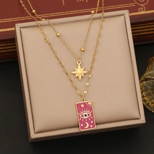 Close-up of gold double-layer necklace with pink enamel eye and star tarot pendants