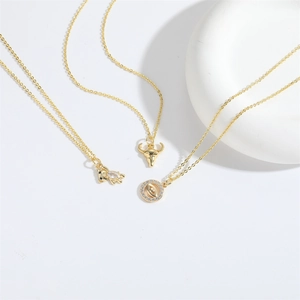 Detailed view of three gold necklaces featuring bear, bull head, and evil eye pendants