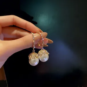 French vintage style pearl drop earrings with zircon crystals held by a model