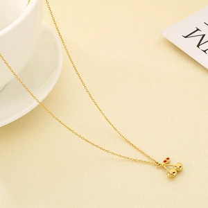 Detailed close-up of golden cherry pendant with red sparkling crystals on a fine chain