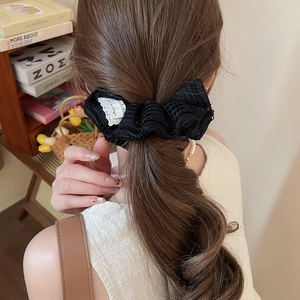 Détail d'un chouchou fleur en tricot noir montré sur une queue de cheval élégante