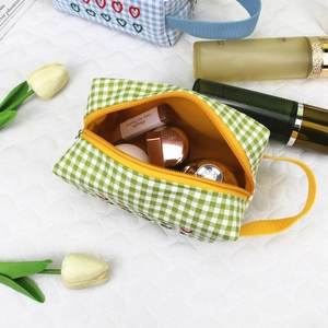 Detailed view of the large capacity green checkered makeup bag with yellow interior and handle