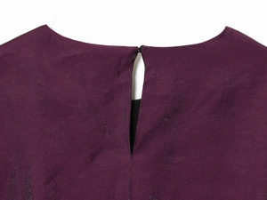 Detail von tiefviolettem Metallic-Stoff mit Tropfen-Ausschnitt und Knopfverschluss