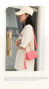 Outdoor lifestyle view of a pink nylon crossbody bag with wide strap and multi-zippers