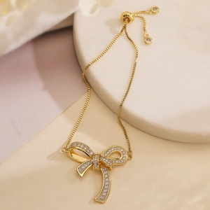 Gold-plated bow bracelet with shimmering cubic zirconia and adjustable pull-chain buckle