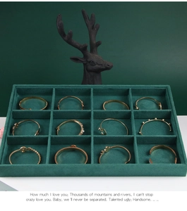 Detailed top view of a dark green velvet 12-slot jewelry tray with golden bracelets