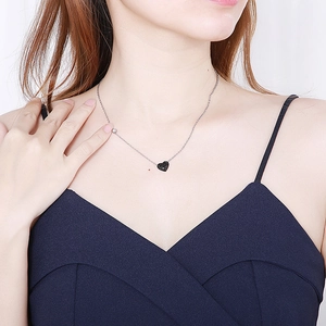 Gros plan d'un collier avec pendentif cœur noir minimaliste porté sur une femme