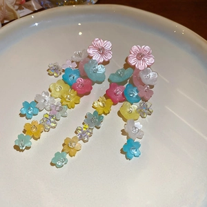Close-up of colorful resin flower tassel earrings with beads on a white plate