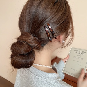 Dettaglio di fermagli per capelli in acrilico tartarugato con elegante scritta del marchio