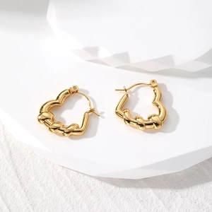 Macro shot of gold-plated geometric heart earrings with unique twisted metal texture detail