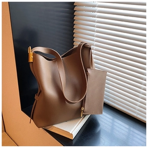 Detail view of brown pebbled leather bucket bag with golden lock and small pouch