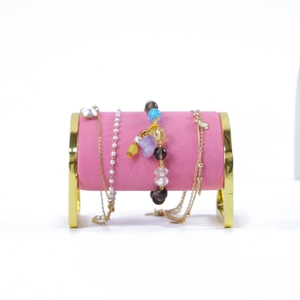 Detail of pink velvet cylinder jewelry stand with elegant gold metal support frame