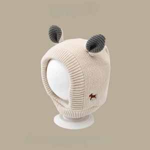 Close-up of knit winter baby hat with ear flaps, grey ear accents and embroidery