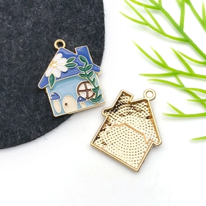 Detailed close-up of a blue enamel house pendant with gold trim and floral patterns