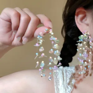Detail of colorful macaron bead tassel earrings with iridescent leaf charms and rhinestones