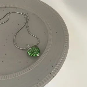 Detailed view of heart-shaped green pendant with zebra stripes on silver snake chain