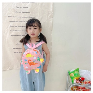 Pink cartoon dinosaur backpack shown on child model with adjustable pink shoulder straps