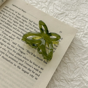Close-up of a green transparent butterfly hair claw clip resting on an open vintage book