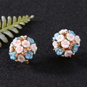 Macro shot of gold floral earrings with blue, white, and pink petals and amber rhinestones