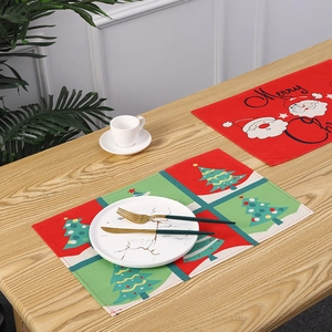Detailed view of Christmas tree and Santa Claus themed dining placemats on a table