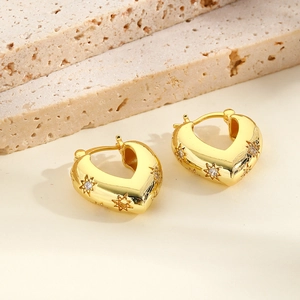 Close-up of gold-plated V-shaped heart earrings with star engravings and cubic zirconia