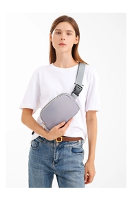 Detail view of a lilac crossbody bag with grey wide strap worn by a model