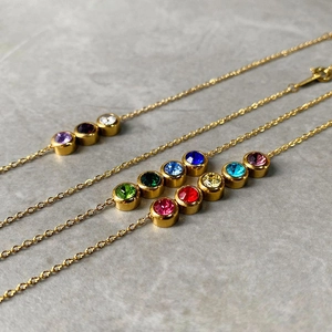 Detailed close-up of a gold bracelet featuring multi-color round rhinestones on grey marble