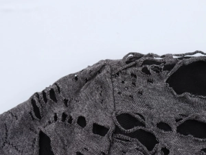 Détail du tissu en maille grise avec déchirures sur un t-shirt à manches longues