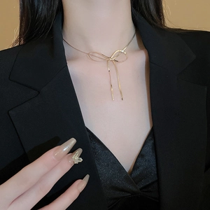 Close-up of golden bow necklace and matching butterfly ring on model for fashion look