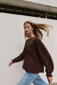 Detail of ethnic boho embroidery and beaded neckline on a burgundy puff sleeve blouse