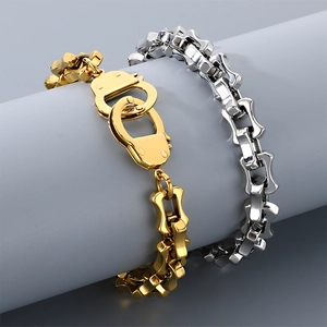 Detail view of gold and silver stainless steel handcuff bracelets on grey pedestal