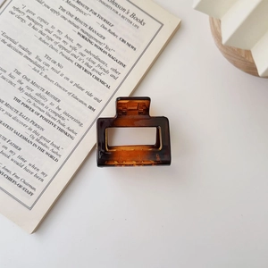 Amber square matte hair claw clip for women placed on a book against a white background