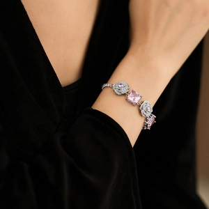 Detailed view of a silver bracelet with pink gemstones and floral zircon charms on wrist