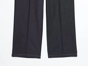 Détails de l'ourlet du pantalon en jean foncé avec surpiqûres orange et plis marqués