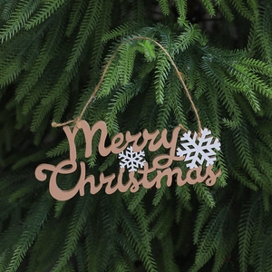 Macro shot of wooden Merry Christmas sign with snowflakes hanging on pine branches