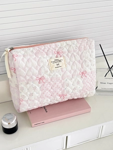 Detailed macro of floral quilted makeup bag featuring pink bows and heart stitching