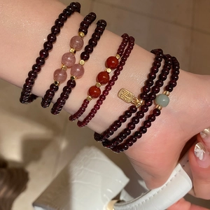 Close-up of layered garnet and strawberry quartz beaded bracelets with gold Fu charm