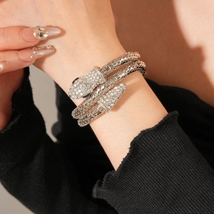 Macro shot of silver snake coil bracelet featuring detailed scales and sparkling rhinestones