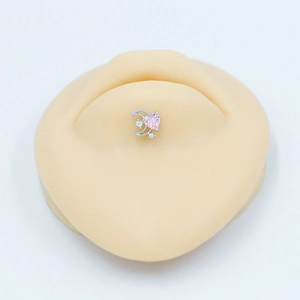 Vue macro de piercing nombril argenté avec cœur rose et zircon lune sur modèle de peau