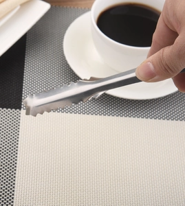 Close-up of stainless steel ice tongs with serrated edges picking up a sugar cube
