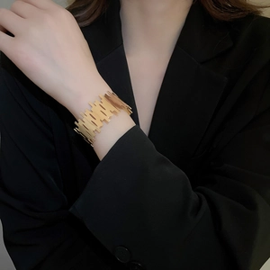 Close-up of golden irregular textured cuff bracelet on wrist over black suit