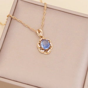 Close-up of gold sunflower necklace with a blue gemstone center in a beige gift box