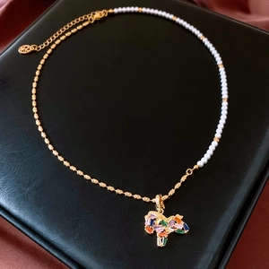 Detail of 18K gold-plated necklace featuring a unicorn pendant with pearls and gemstones