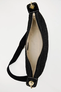 Detailed view of black woven texture bag with gold zipper and beige inner lining