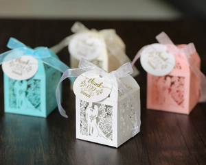 Hollow laser-cut wedding favor boxes with satin ribbons and Thank You tags on wood