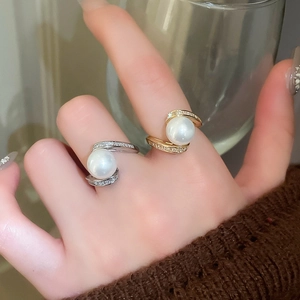 Détail de bagues serpent dorées et argentées avec perles blanches et zircons brillants