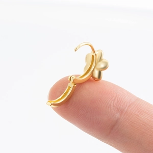 Golden flower hoop earring in copper with cubic zirconia shown on finger for scale