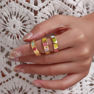 Close-up of three gold 18K plated rings with colorful enamel stars and smiley faces on lace