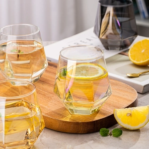 Detailed macro shot of hexagonal diamond-cut glass cups on a wooden tray with lemon slices