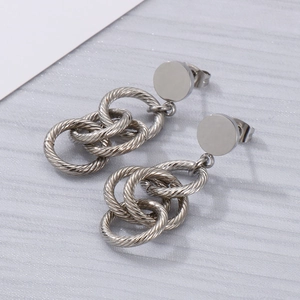 Détail de boucles d'oreilles pompons argentées avec anneaux métalliques texturés